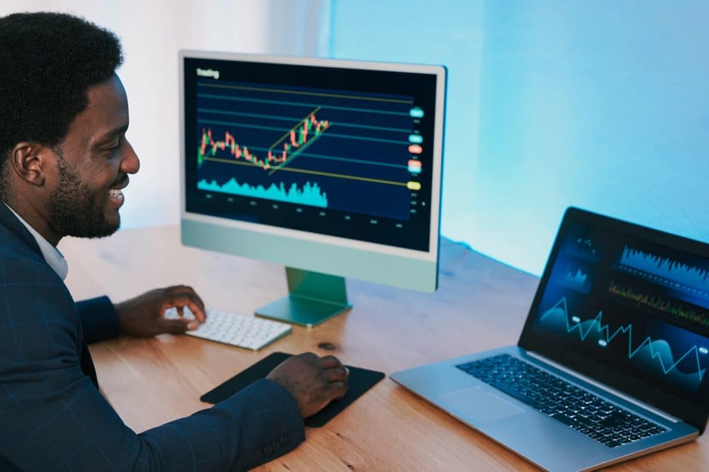 African trader man working inside hedge fund office doing stock market analysis